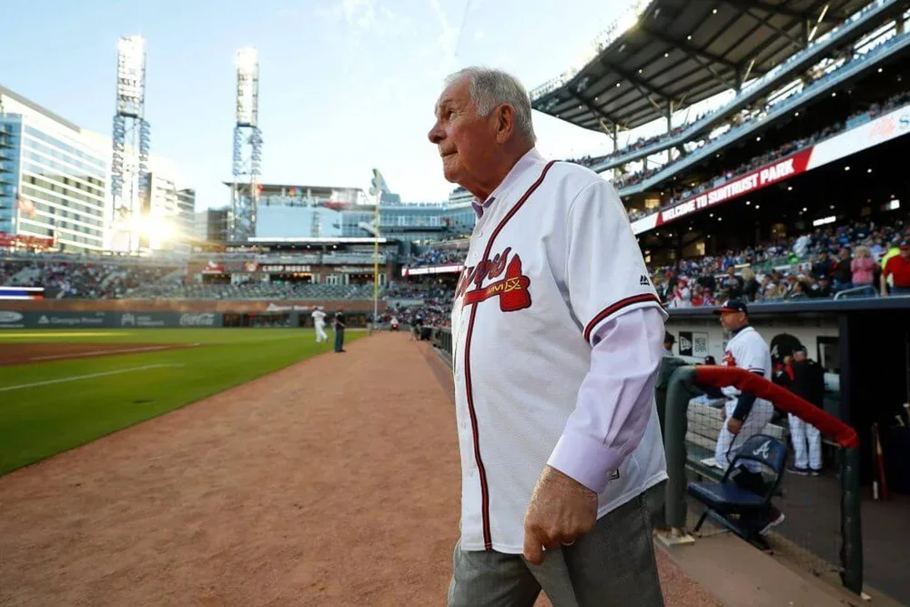Bobby Cox walks walks onto the field while wearing a Braves jersey.