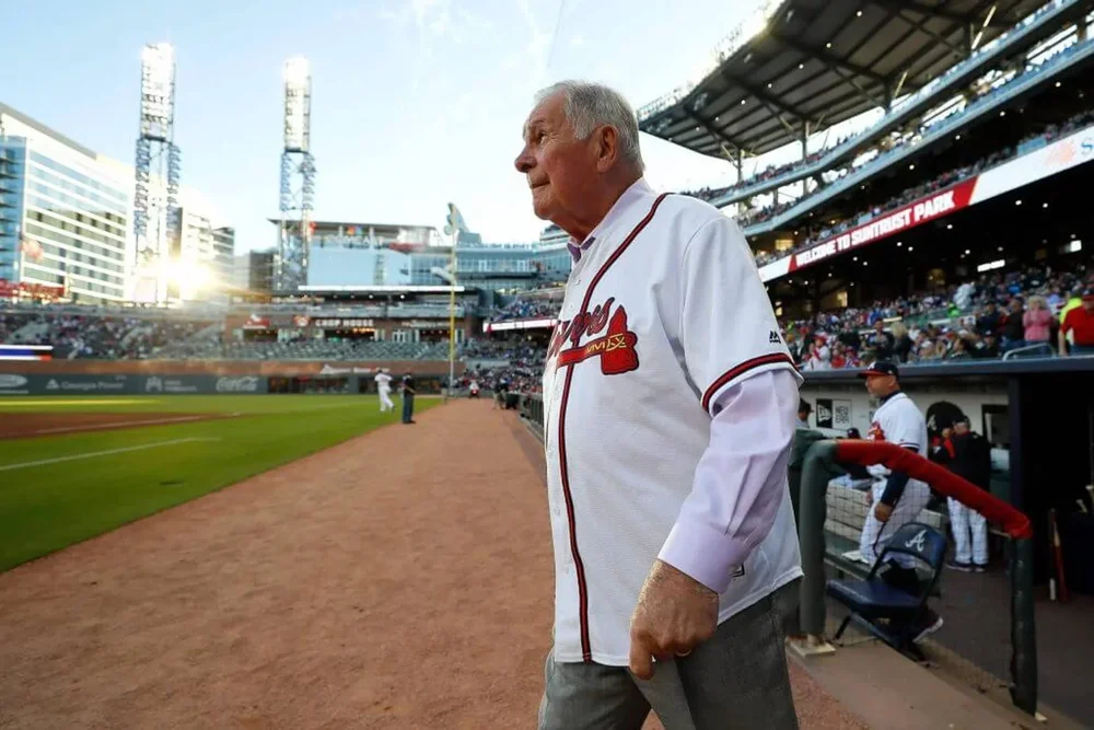 Bobby Cox walks walks onto the field while wearing a Braves jersey.